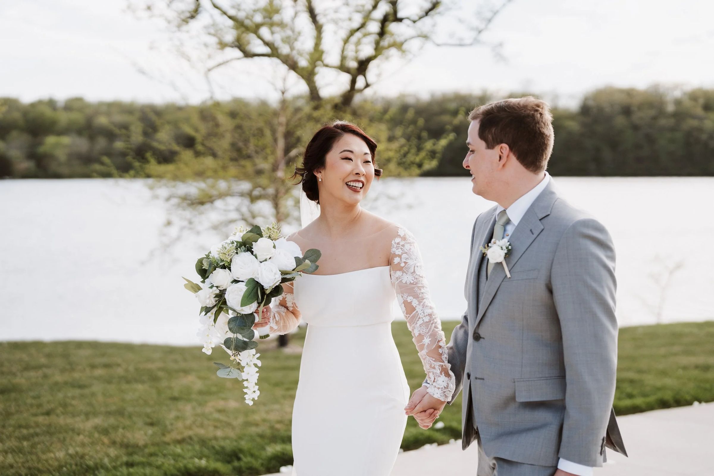 Ji Eun and Andrei walking hand in hand by the lake, laughing, just after the ceremony